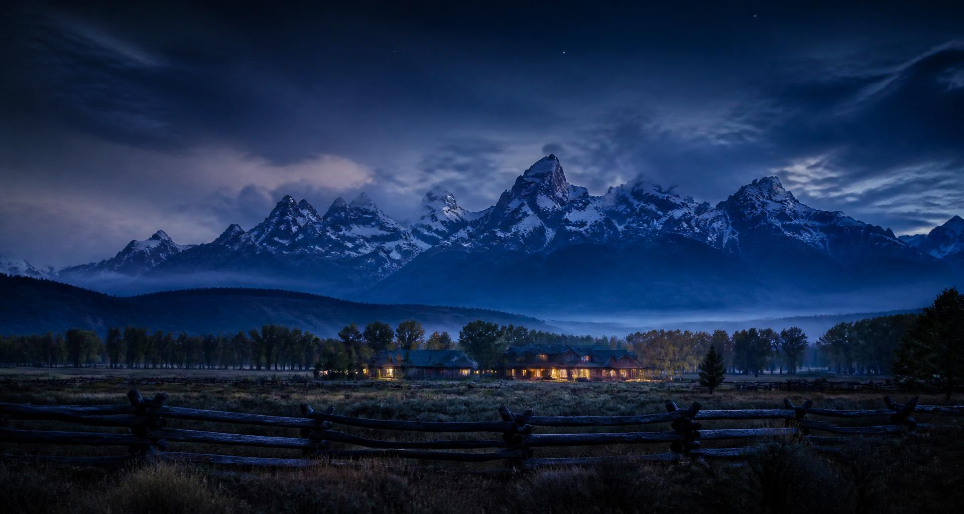 Teton Valley at blue hour with snow-capped peaks, valley mist, and warm ranch lights